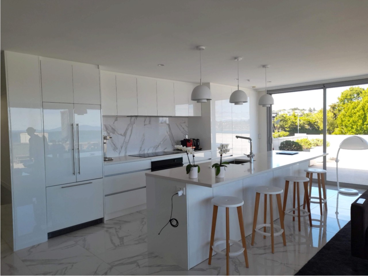 White kitchen with marble splashback and a view